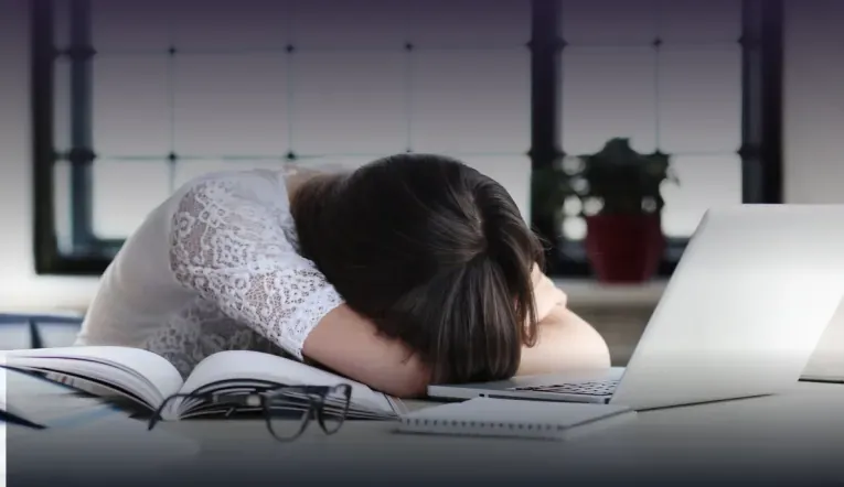 Imagem princial: Mulher cansada de tanto estudar dormindo em cima da mesa na frente do seu notebook